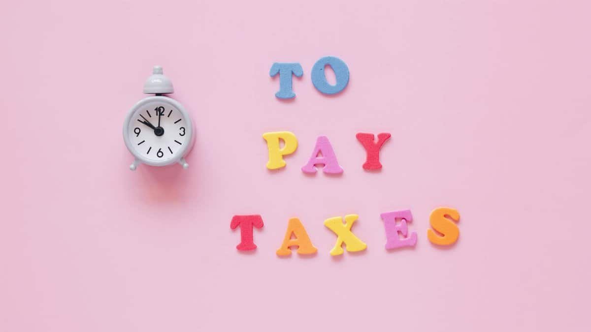 Creative tax payment reminder with clock and colorful letters on a pink background.