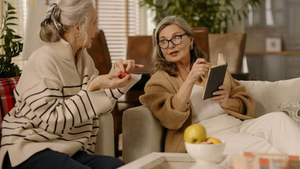 Two senior women having a warm and intimate conversation on a cozy couch indoors.
