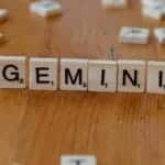 Gemini zodiac sign spelled with Scrabble tiles on a wooden table.