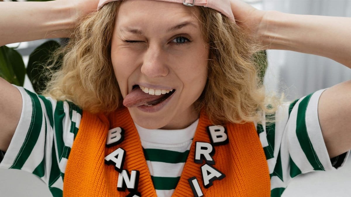 Young woman playfully sticking her tongue out with text BANANA BRAIN. Indoors, humorous style.