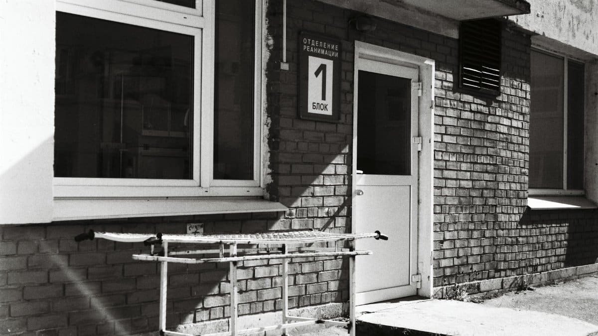 Monochrome image of a hospital entrance featuring a gurney and a brick building.