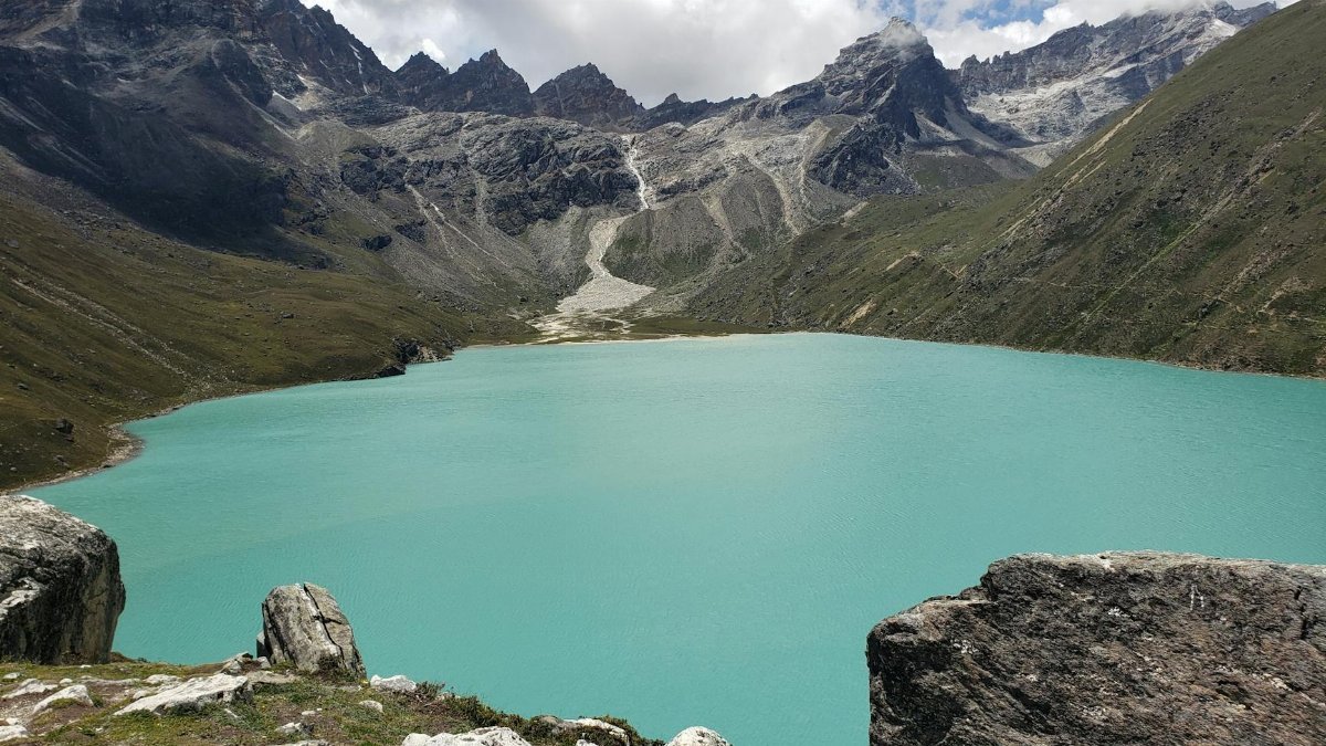 Serene view of Gokyo Lake with surrounding majestic mountains in Sagarmatha National Park, Nepal.