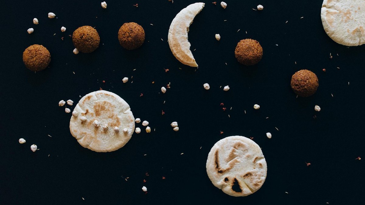 Creative flat lay of pita bread and falafel arranged like celestial bodies.