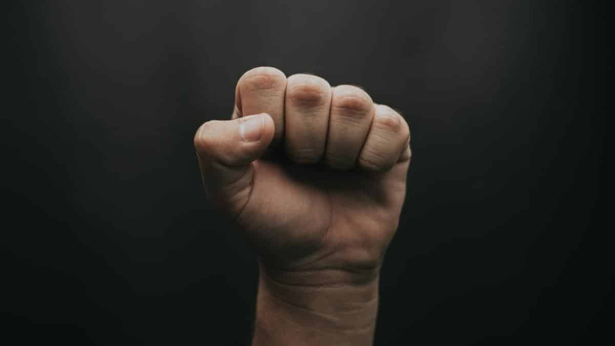 A close-up of a fist raised against a dark background, symbolizing strength and unity.