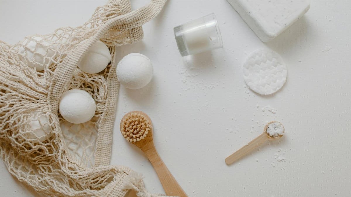 Minimalist flat lay of eco-friendly bath essentials including bath bombs, soap, and a brush.