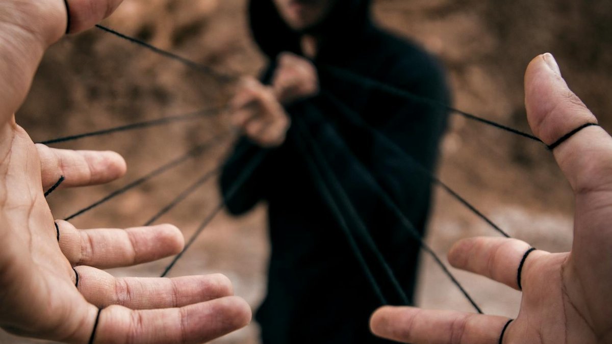 Conceptual image of a man controlling hands with strings, reflecting manipulation.