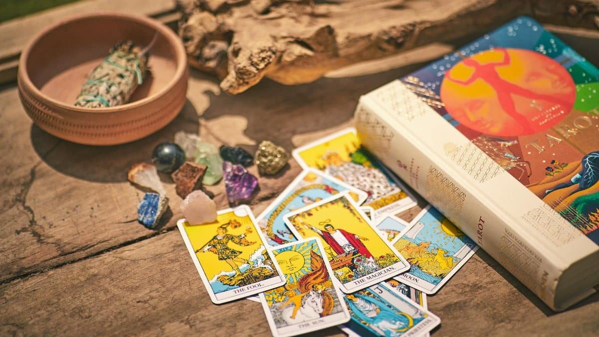 Colorful tarot cards with crystals and sage on rustic table evoke mystical and spiritual themes in Dubai.