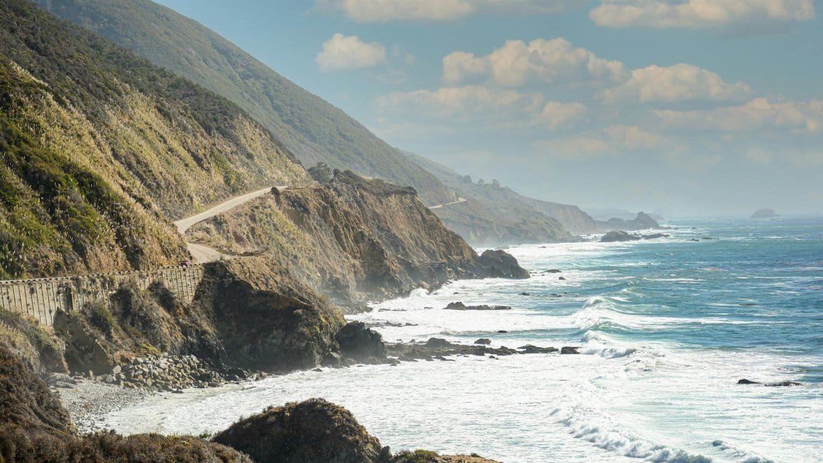 Captivating view of California's coastal highway along the rocky shore with ocean waves crashing.