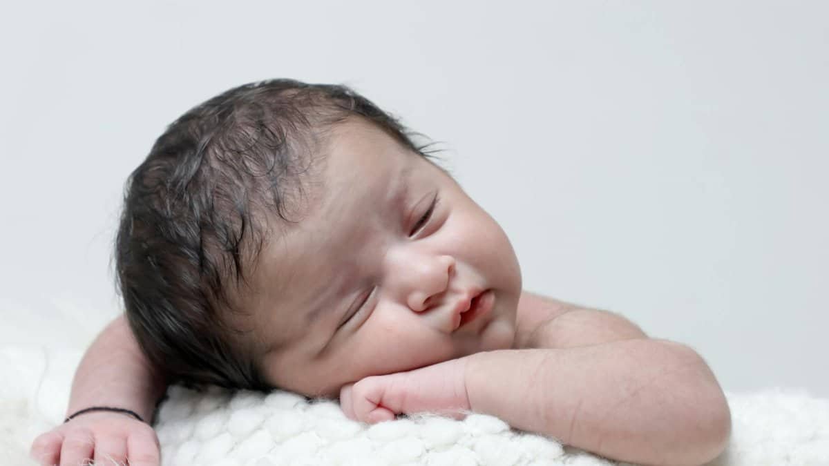 A serene image of a newborn baby sleeping on a soft white blanket, capturing innocence and tranquility.