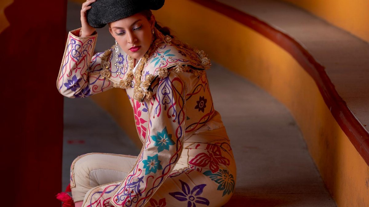 A vibrant portrait of a person in traditional matador attire with intricate embroidery, seated in a colorful setting.