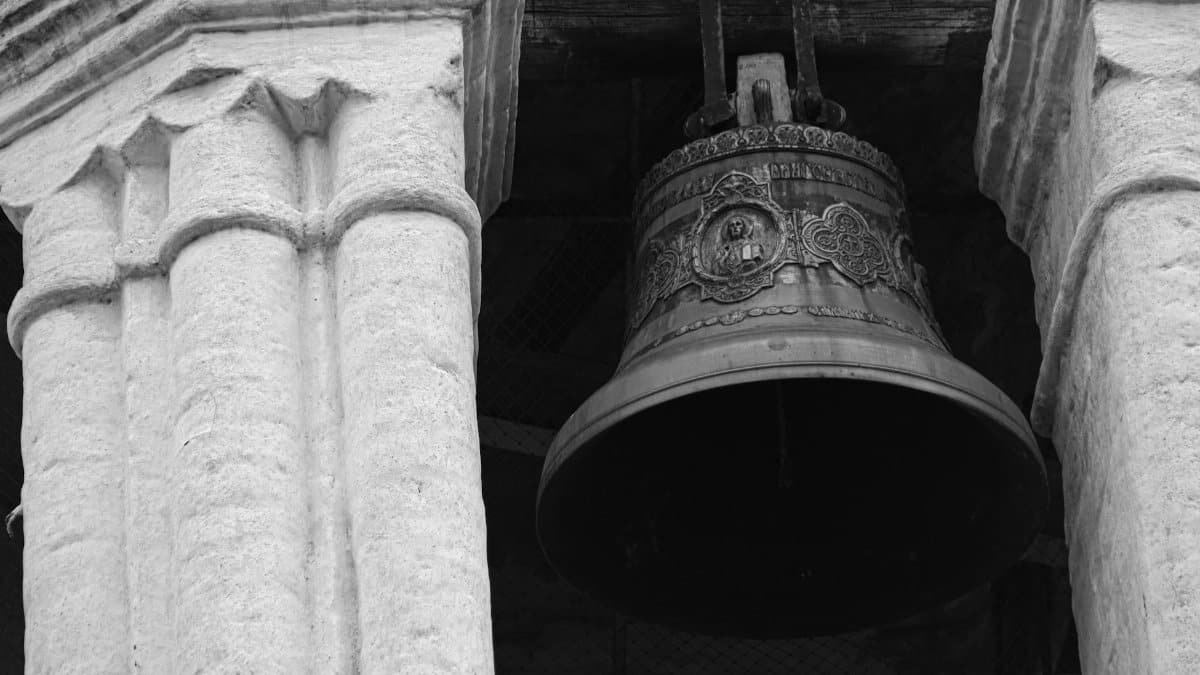 Black and white image of a detailed cathedral bell with stone pillars.