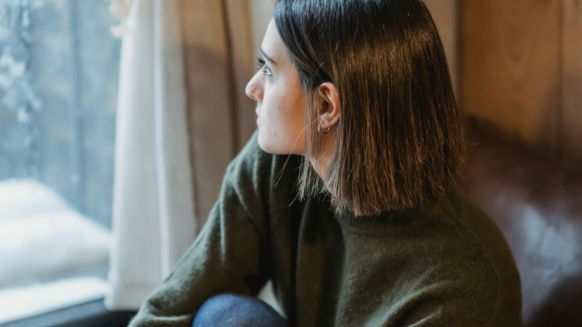 Thoughtful young woman gazing out a window, exuding serenity and contemplation.