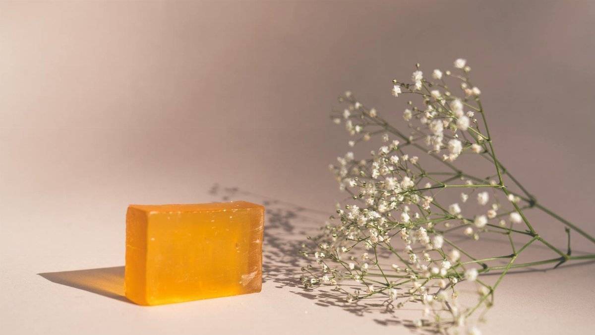 A bar of orange soap next to baby's breath flowers in a minimalist setup.