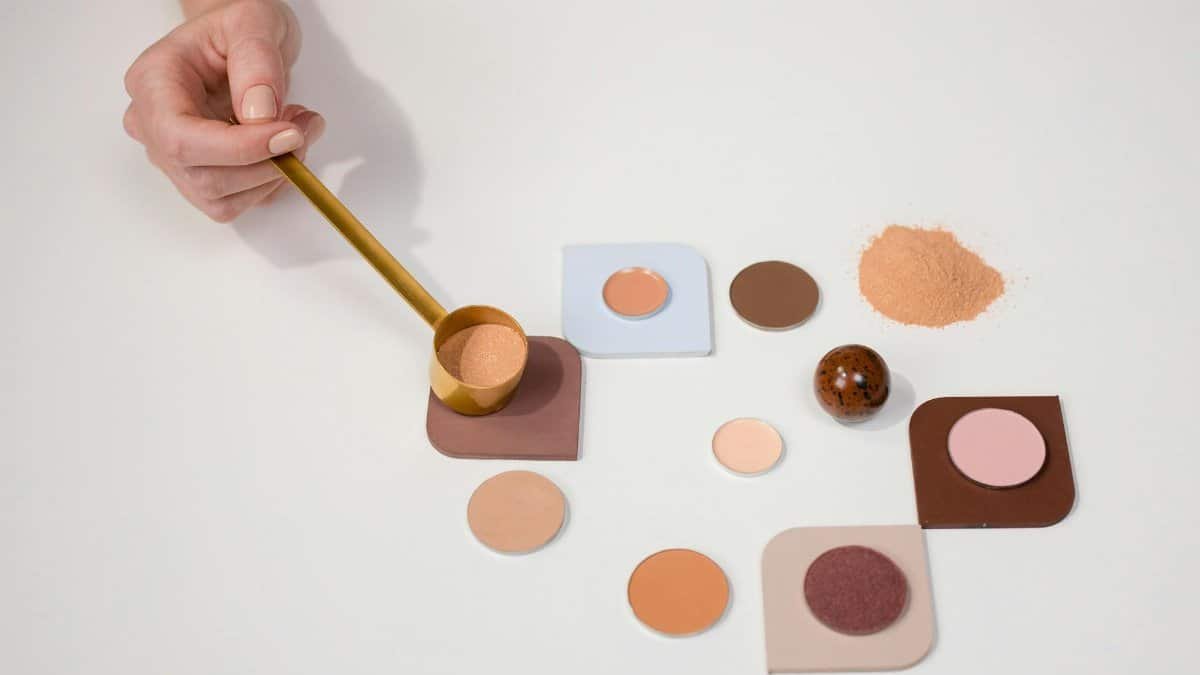 Flat lay of makeup powders and palette with a hand holding a brush for beauty concepts.