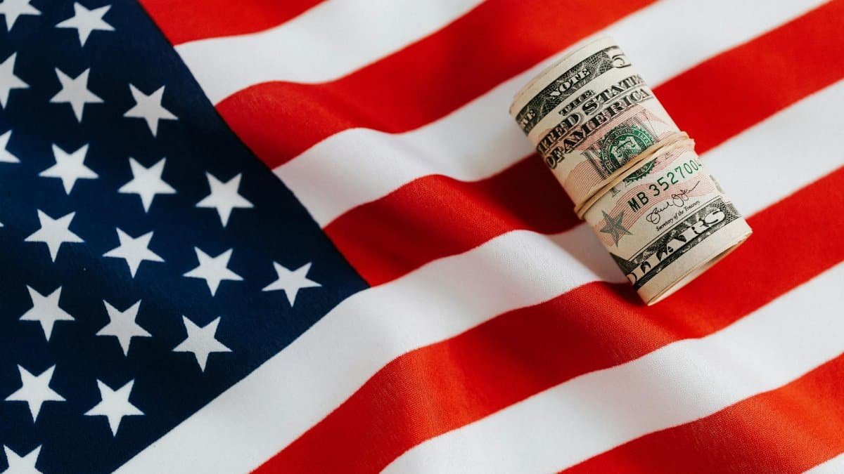 From above of United States currency folded in roll placed on USA flag illustrating concept of business profit and wealth