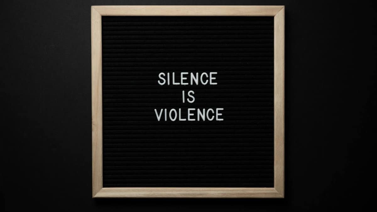 Message reading 'Silence is Violence' on a black felt board with wooden frame.