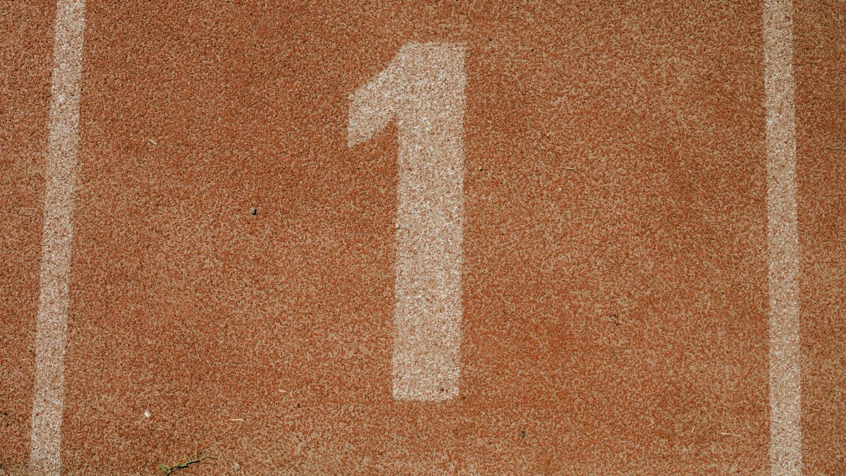 Close-up image of number one lane on a running track, symbolizing first place.