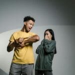 A man holds a snake while a woman appears scared, depicting a moment of fear and anxiety.