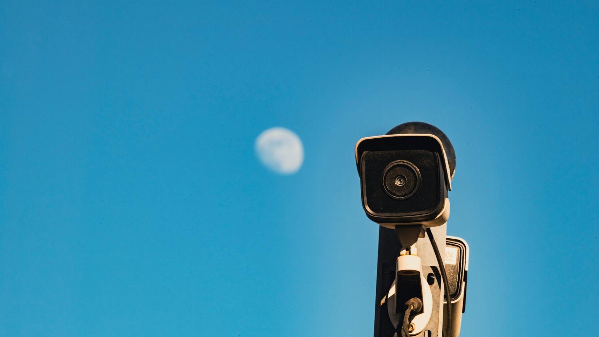 A CCTV surveillance camera with a blue sky and moon in the background, capturing urban security essence.