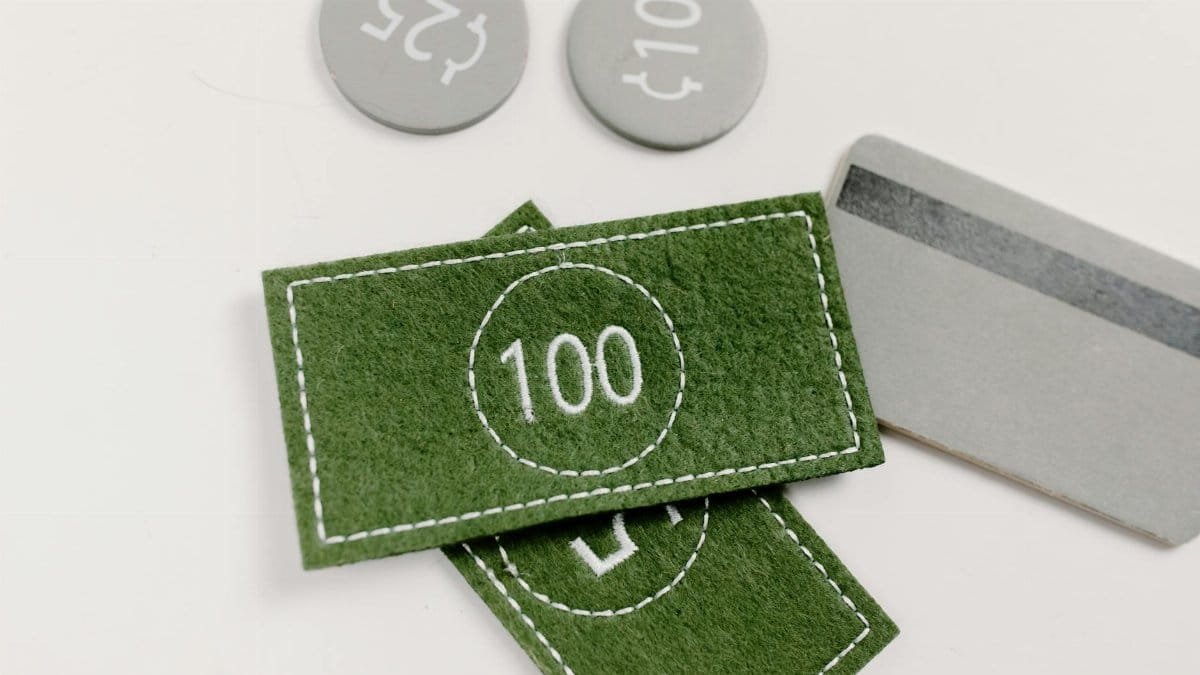 Creative representation of financial concepts using felt currency and cards on a white background.