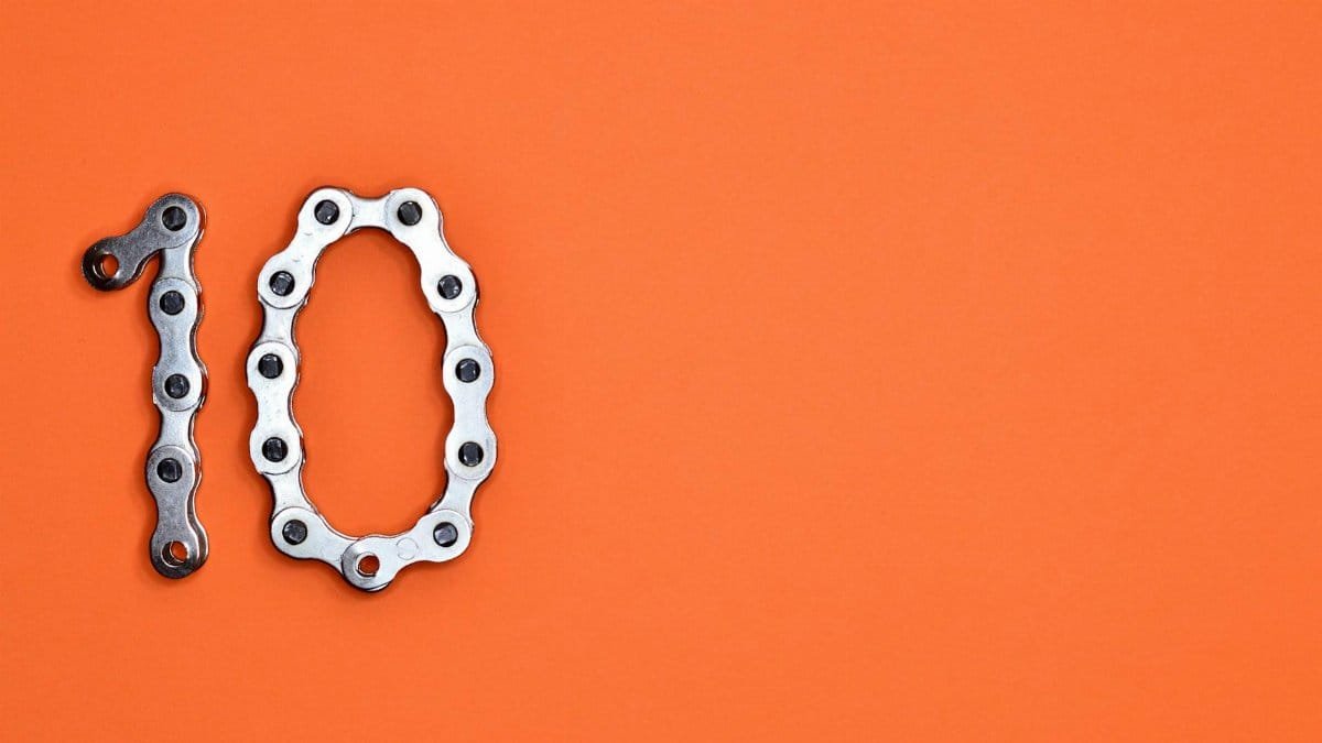 Bicycle chain arranged to form the number ten against a bright orange background.