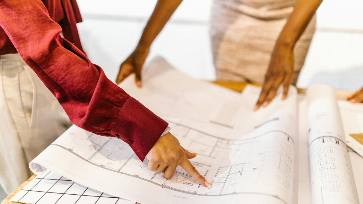 Two women collaborate on architectural plans in a modern office setting.