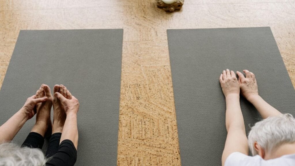 Two senior adults practicing yoga indoors, focusing on relaxation and flexibility.