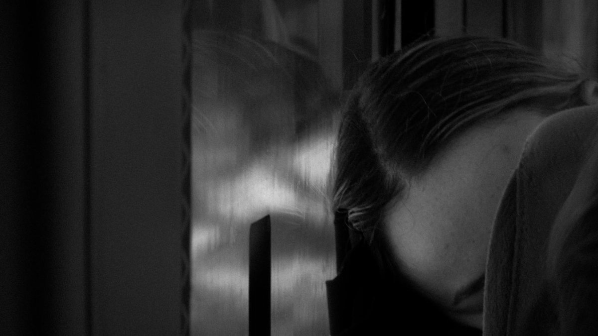 A person resting their head on a train window, captured in black and white, evokes a serene and reflective mood.