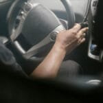 High angle of crop unrecognizable male driving modern car on street on sunny day