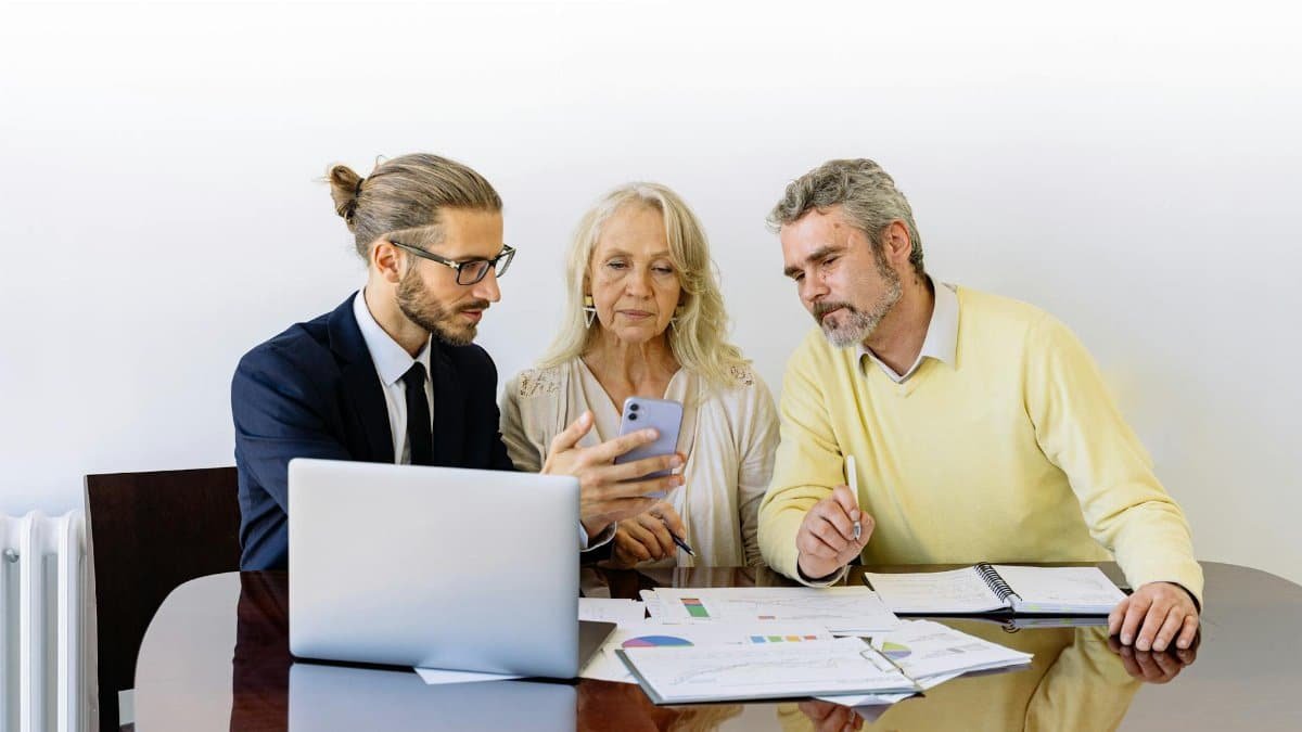 Three individuals collaborating on financial documents during a business meeting.
