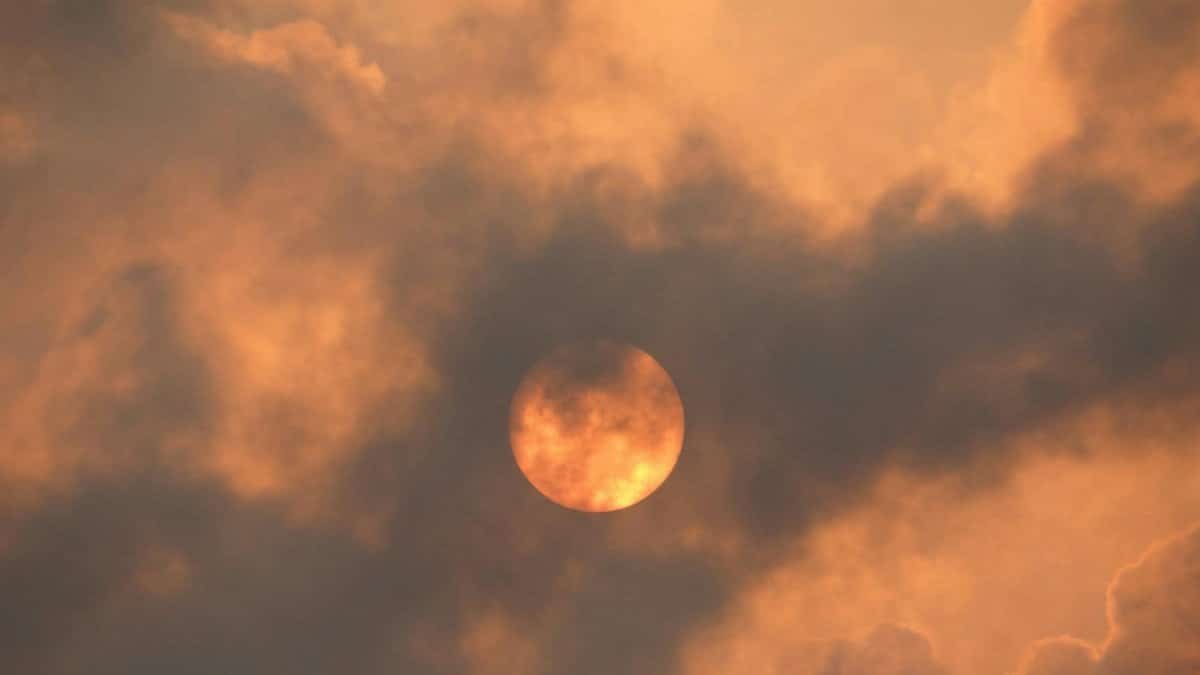 A dramatic cloudscape with the sun casting warm hues, creating a striking visual contrast in the sky.