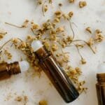Brown roll-on bottles with dried chamomile flowers on a white background.