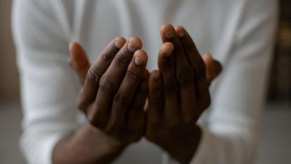 A close-up shot of an African American man's hands in a prayer gesture, conveying spirituality and tranquility.