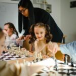 Kids engaging in a chess game with teacher guidance in a classroom.