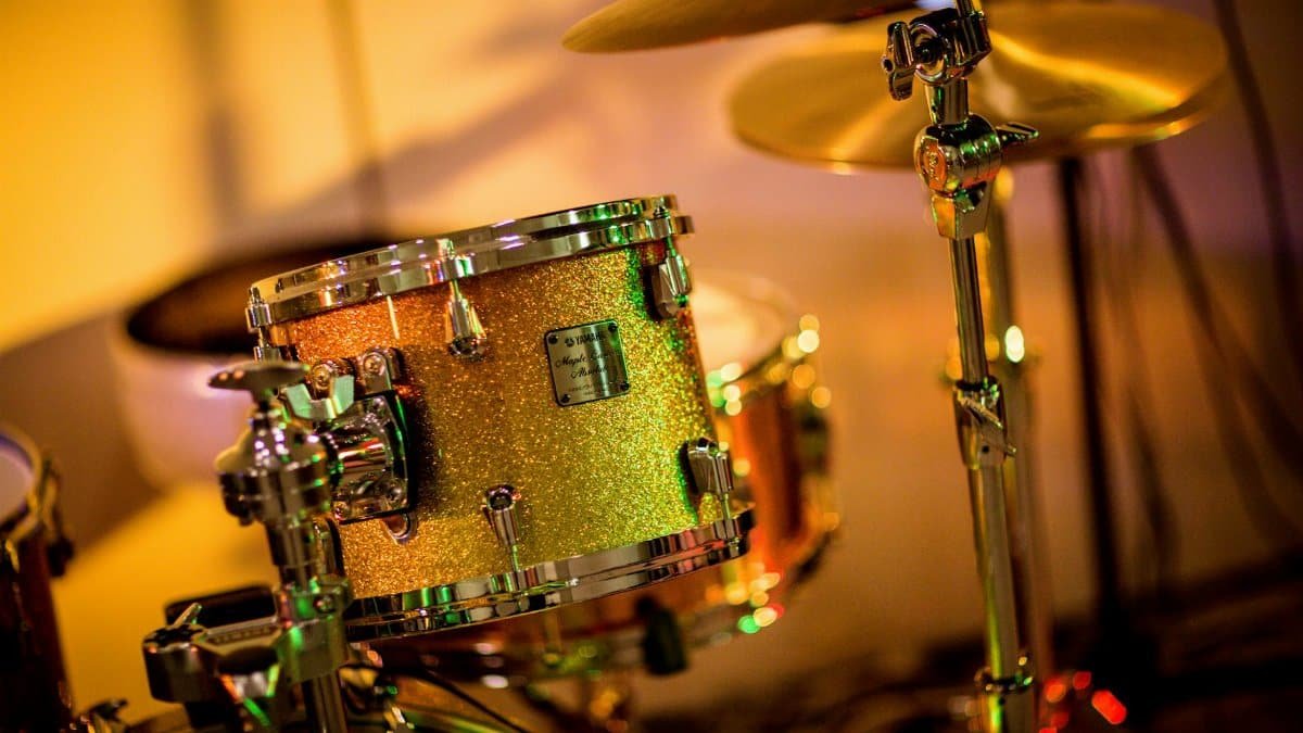 A vibrant close-up photo of a glittery drum set under concert lights, evoking a lively music performance.