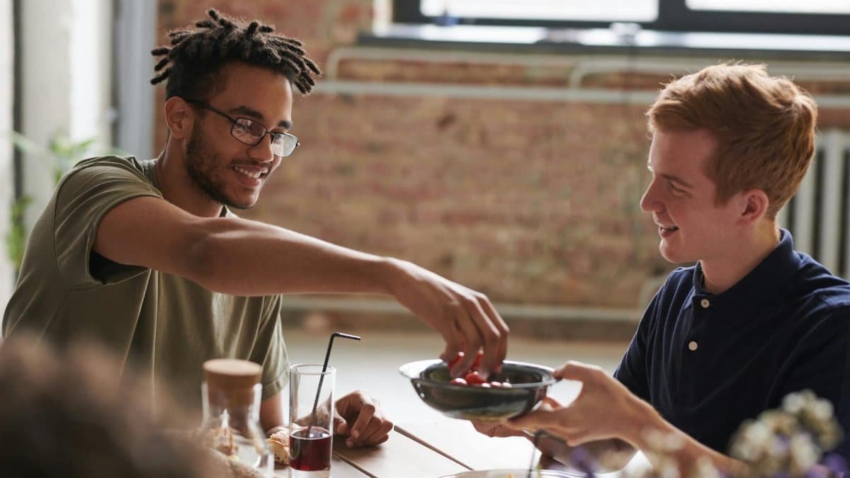 Two friends enjoying a relaxed indoor meal, sharing food and drinks.