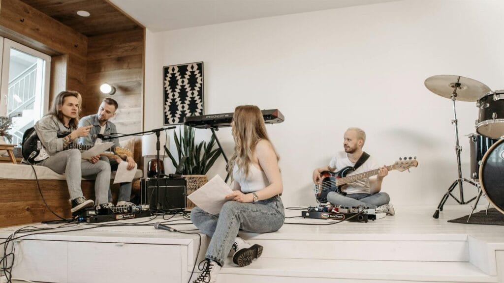 A group of young musicians rehearsing with instruments in a modern studio setting.