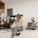 A group of young musicians rehearsing with instruments in a modern studio setting.