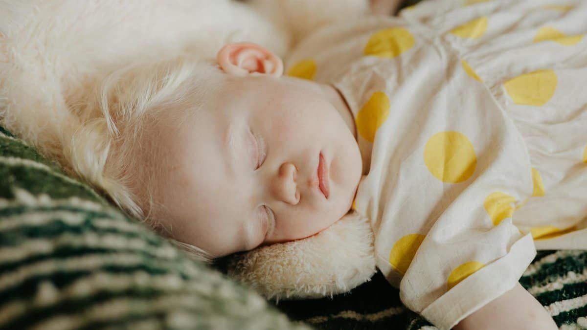 A serene image of a baby in a yellow polka dot dress sleeping peacefully indoors.