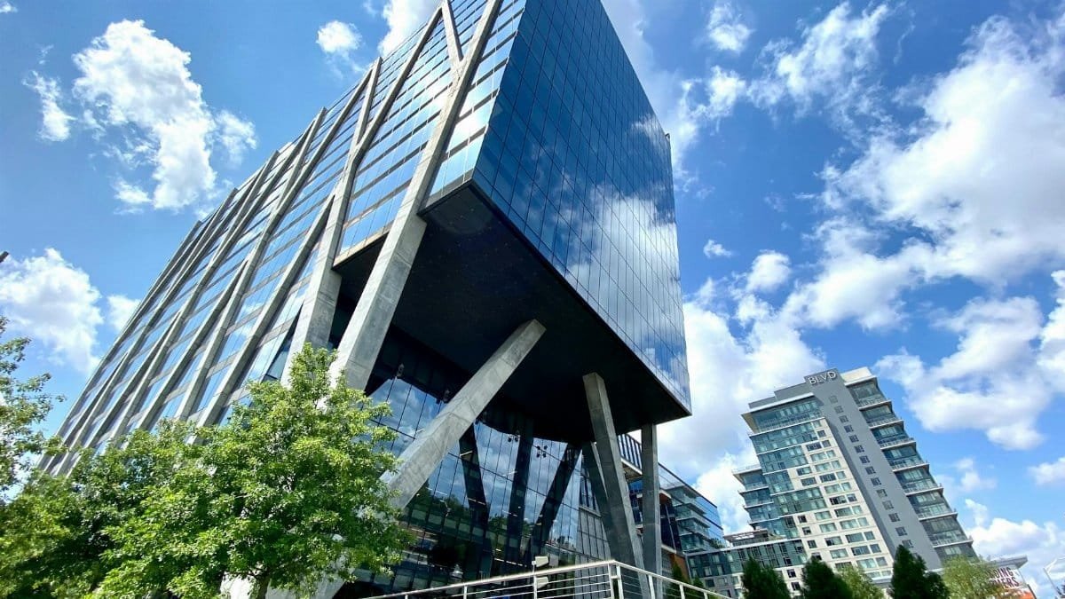A striking modern office building with glass facade in Reston, VA under a clear blue sky.