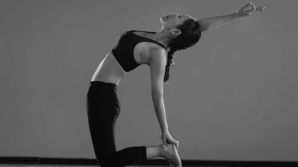 A woman gracefully performing a yoga pose indoors, showcasing balance and flexibility.