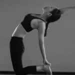 A woman gracefully performing a yoga pose indoors, showcasing balance and flexibility.