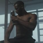 A dedicated athlete uses a massage gun to relax his muscles post-workout in the gym.