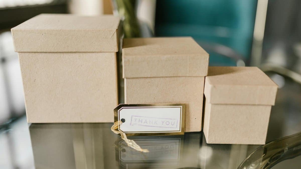 Three brown cardboard boxes on a glass table with a tag reading 'Thank You.', perfect for gifting concepts.