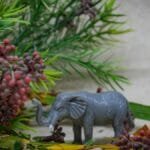 Toy elephant among lush greenery and berries for nature-inspired decor.