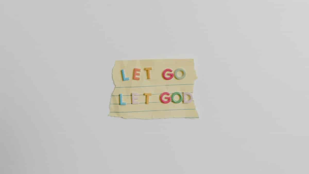 Minimalist image of a torn paper with the phrase 'Let Go, Let God' in colorful letters.