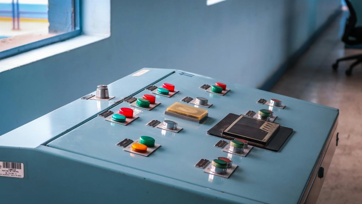 Close-up of an industrial control panel with colorful buttons in a factory setting.