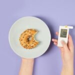 A bitten donut on a plate and a glucometer symbolizing sugar levels and diabetes awareness.