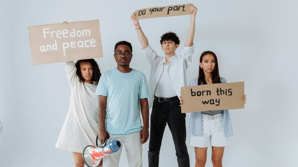 A group of diverse young adults holding protest signs promoting peace and unity.