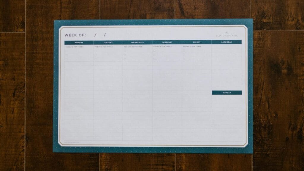 Top view of a blank weekly planner on a wooden surface, perfect for organizing your week.